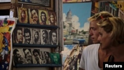Tourists look at portraits of revolutionary leader Che Guevara at an artisans' fair in Havana, Oct. 8, 2013.