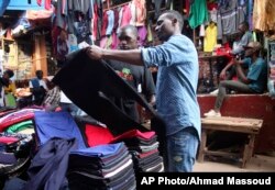A man looks at second hand trousers at a market in Kampala, Uganda, April 6, 2018. The used clothes cast off by Americans and sold in bulk in African nations have been blamed in part for undermining local textile industries.