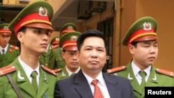 Cu Huy Ha Vu is escorted by policemen after his trial at a court in Hanoi April 4, 2011. Vu, a legal scholar who sued Vietnam's prime minister and called for an end to one-party rule, was sentenced on Monday to seven years in prison.