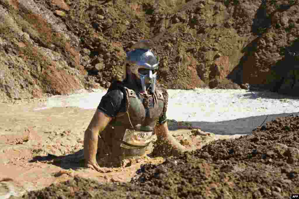 A competitor wearing a gladiator outfit crosses a pit of mud during the Strongman Run obstacle race in the South African city of Paarl, about 60km from Cape Town, Oct. 13, 2018.