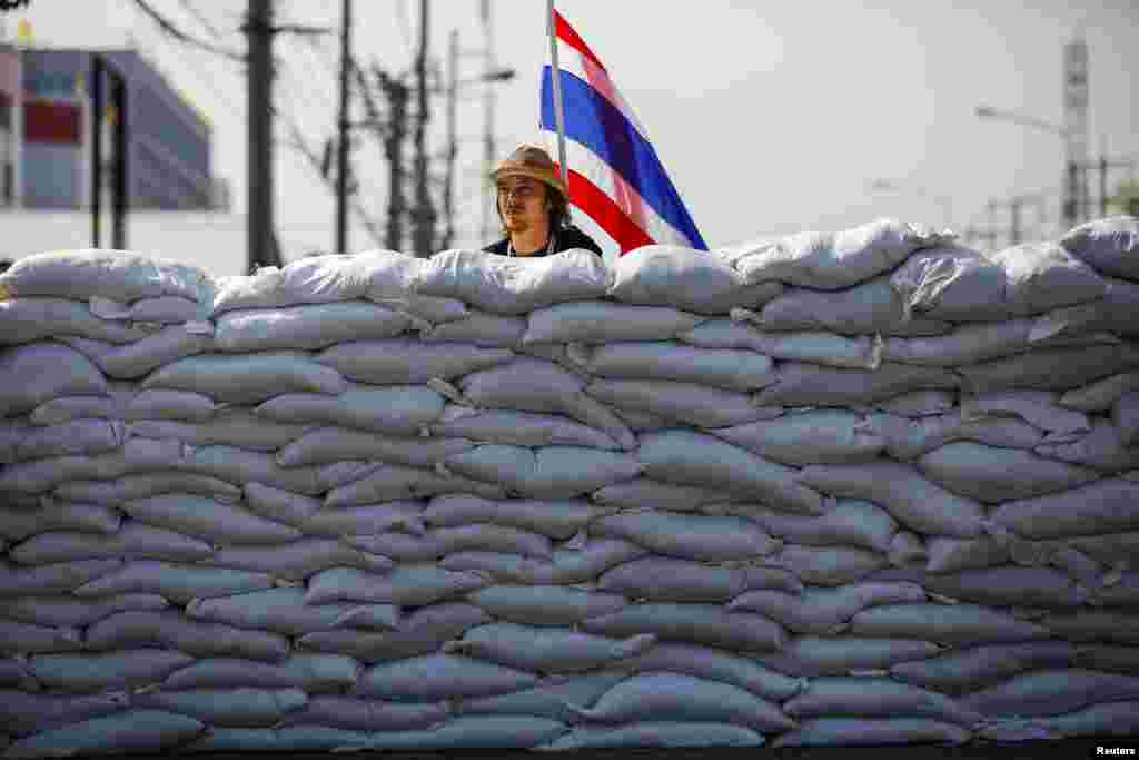 An anti-government protester stands behind a barricade in a major intersection in central Bangkok, Jan. 13, 2014. 