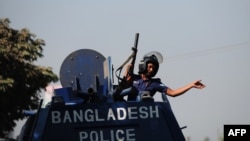 A Bangladeshi policeman gestures from an armored car after clashes with Bangladesh Nationalist Party (BNP) activists and its Islamist allies during a blockade in Aminbazer, in the outskirts of Dhaka, Nov. 26, 2013. 