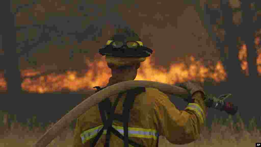 Un pompier regarde le brûlemenrt du feu,13 août 2015