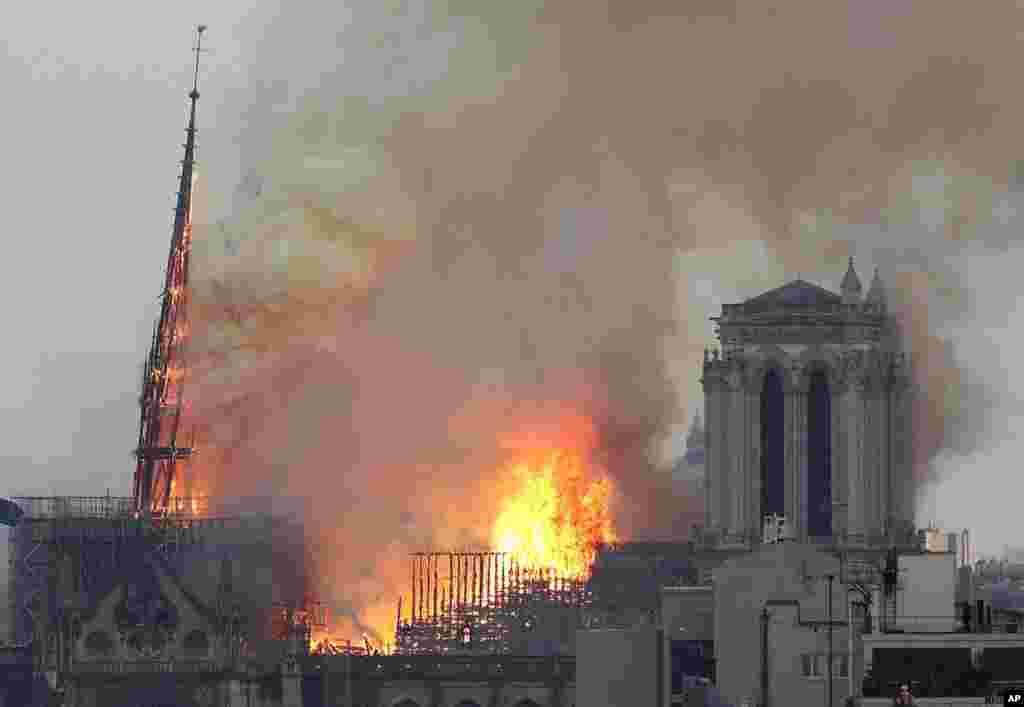 نوٹرڈیم کی مخروطی چوٹی شعلوں میں گھری ہوئی نظر آ رہی ہے اور آگ کے شعلے اور دھواں چھت سے اوپر اٹھ رہا ہے۔