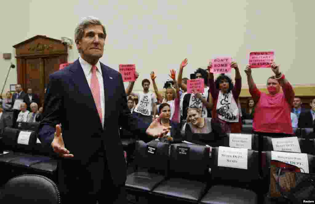 Para demonstran anti perang membawa poster menentang intervensi militer AS di Suriah, saat Menteri Luar Negeri John Kerry muncul di Gedung DPR AS untuk menghadiri sidang membahas rencana serangan militer AS di Suriah.