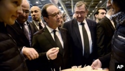 France's President Francois Hollande, center, samples some cheese as he visits the Paris international agricultural fair, Feb. 21, 2015.