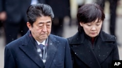 FILE - Japanese Prime Minister Shinzo Abe, left, and his wife Akie Abe take part in a wreath laying ceremony at the Antakalnis Memorial Cemetery in Vilnius, Lithuania, Jan. 14, 2018.