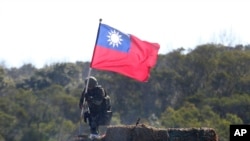 资料照片：一名台湾士兵手举台湾旗帜参加新竹举行的军演模拟反击中国军队攻台。（2021年1月19日）