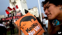 A man holds a sign during a protest against presidential candidate Keiko Fujimori and against the 1992 coup by her father, former President Alberto Fujimori, in downtown Lima, Peru, Tuesday, April 5, 2016.
