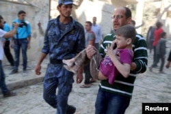 FILE - A man holds an injured boy after what activists said was a barrel bomb dropped by forces loyal to Syria's President Bashar al-Assad.