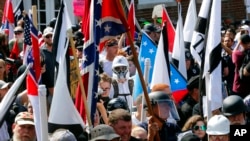 FILE - White nationalist demonstrators walk into the entrance of Lee Park surrounded by counterdemonstrators in Charlottesville, Va., Aug. 12, 2017. 