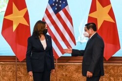 Perdana Menteri Vietnam Pham Minh Chinh (kanan) memberi isyarat kepada Wakil Presiden AS Kamala Harris di kantor Pemerintah di Hanoi, Vietnam, 25 Agustus 2021. (Manan Vatsyayana/Pool via REUTERS)