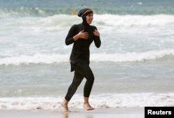 Twenty-year-old trainee volunteer surf life saver Mecca Laalaa runs in a burkini at the beach.