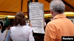 People check prices of products in a street market in Caracas, Venezuela, Aug. 18, 2018. President Nicolas Maduro has unveiled a major economic reform plan that takes effect Monday.