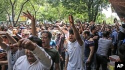 In this June 25, 2018 file photo, a group of protesters chant slogans at the old grand bazaar in Tehran, Iran.