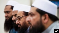 FILE - Hafiz Saeed, second from right, chief of Pakistani religious group Jamaat-ud-Dawa listens to reporters at a news conference in Islamabad, Pakistan, Nov. 2, 2015.