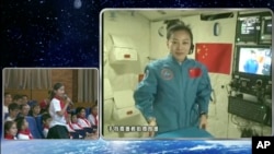 In this image taken and made from CCTV, Chinese astronaut Wang Yaping, seen on screen, listens to a question from a school girl in Beijing, China, during a live broadcast from onboard the Tiangong 1 space station, June 20, 2013.