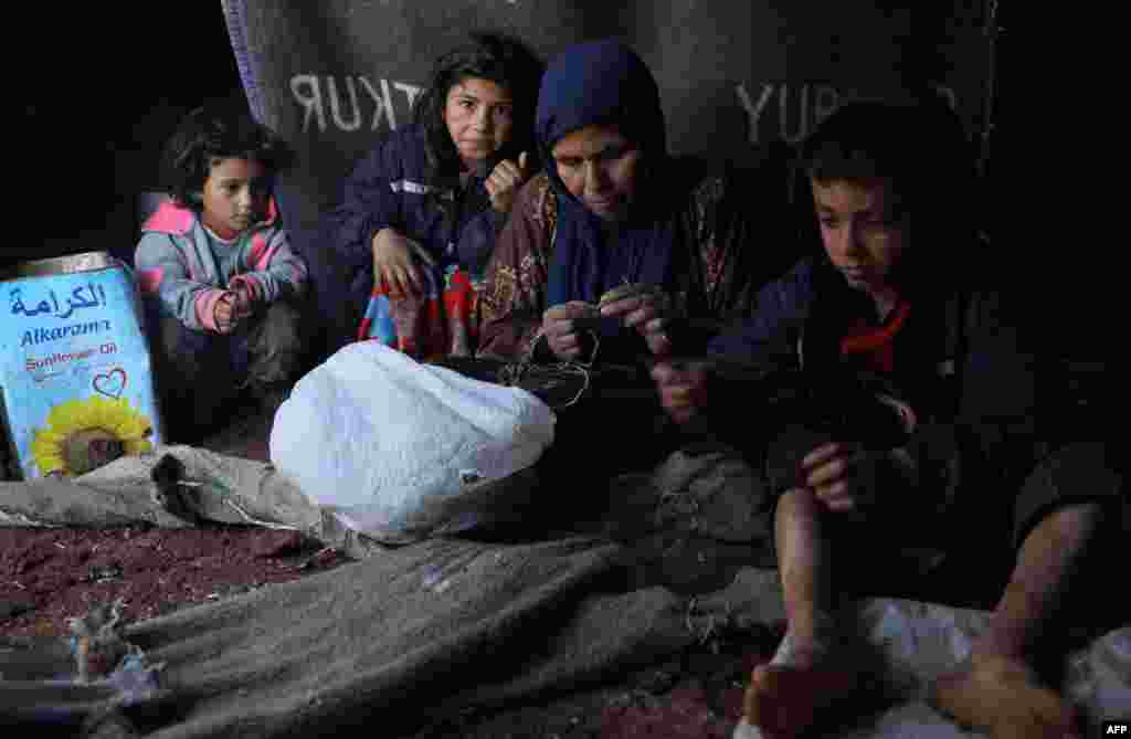 시리아 알레포에서 내전을 피해 이들리브의 임시 캠프로 피난온 실향민들이 비로 인해 젖은 텐트 속에 앉아 있다.