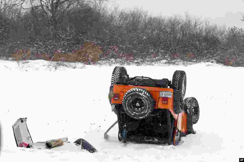 Sebuah mobil terbalik setelah berputar tanpa kendali di jalan selama badai salju (2/1) di Portland, Maine, tempat sejumlah kecelakaan serupa di jalan layang dilaporkan. (AP/Robert F. Bukaty)