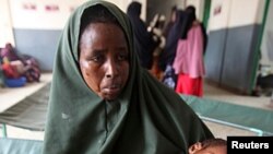 A woman holds her malnourished child on arrival at Banadir hospital in Mogadishu, Somalia, July 7, 2011.