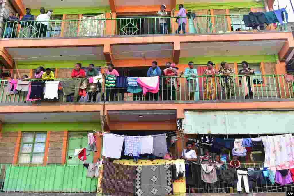 People stand on their balconies next to a collapsed six-story building in the Kenyan capital of Nairobi, as search and rescue operations continue.