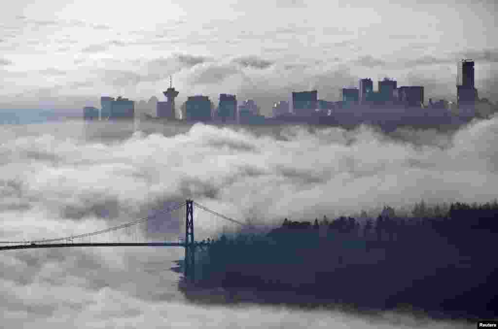 Khu trung tâm thành phố và cầu Lions Gate bao phủ trong sương sớm tại Vancouver, Canada.