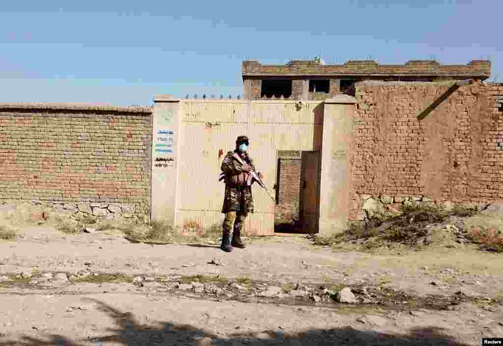 Taliban əsgəri Taliban qüvvələrinin basqın etdiyi İslam Dövləti sığınacağına qonşu bir evin qarşısında keşik çəkir