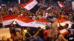 Demonstrators chant in support of Iraqi Prime Minister Haidar al Abadi as they wave national flags during a demonstration at Tahrir Square in Baghdad, Iraq, August 9, 2015.