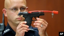 Sĩ quan cảnh sát Timothy Smith cầm khẩu súng đã được sử dụng để giết Trayvon Martin trong khi làm chứng tại tòa án Seminole ở Sanford, Florida. 