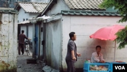 A woman sells what appears to be bread and beverages in Kujang, North Korea, July 24, 2013. (VOA/Steve Herman)