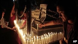 Exiled Tibetans light candles in front of portraits of 21-year-old monk Phuntsog, during a candlelit vigil to honor the monk who set himself on fire in an anti-government protest, in Dharmsala, India, March 17, 2011