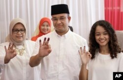 Anies Baswedan, center, and his family show their ink-dipped fingers after voting in the local election in Jakarta, Indonesia, April 19, 2017.