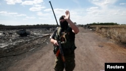 FILE - An armed pro-Russian separatist gestures to reporters at the crash site of Malaysia Airlines Flight MH17, near the village of Grabovo, Donetsk region, Crimea, July 21, 2014.