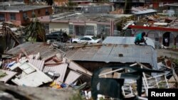 Seorang laki-laki berupaya membangun kembali rumahnya setelah Badai Maria melanda Puerto Riko.