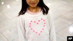 FILE - Janet Mejia, 7, wears a sweater bearing a heart as she waits for two siblings to arrive from El Salvador in Linthicum, Md., Nov. 12, 2015. They were among the first teens to receive permission to travel legally to the U.S. via the Central American Minors program.
