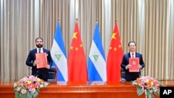 Laureano Ortega Murillo, hijo y asesor del presidente de Nicaragua, Daniel Ortega, a la izquierda, y el vicecanciller chino, Ma Zhaoxu, muestran su comunicado sobre la reanudación de las relaciones diplomáticas entre los dos países en Tianjin, China, 10 de diciembre de 2021.