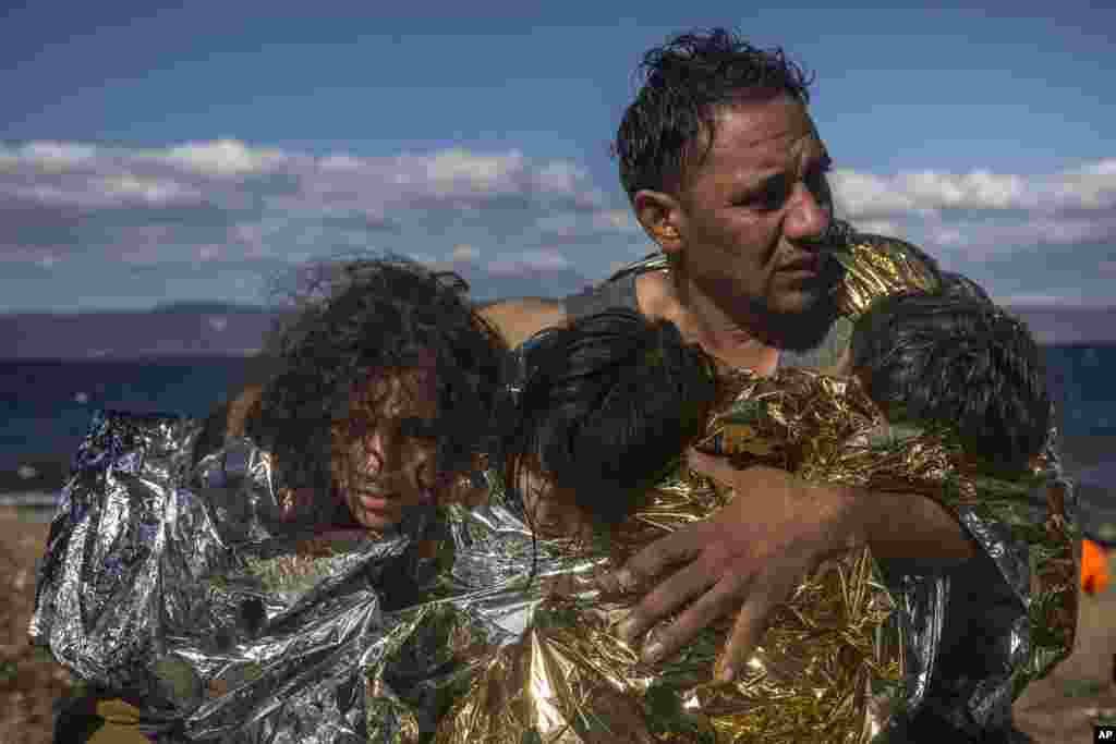 터키에서 바다를 건너 그리스 레스보스 섬에 도착한 남성과 세 자녀가 보온 담요를 덮고 있다.