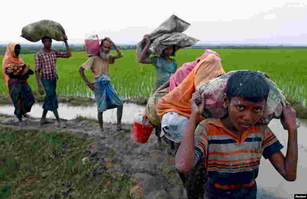 Rohingya refugees walk on a muddy path after crossing the Bangladesh-Myanmar border, in Teknaf, Bangladesh.