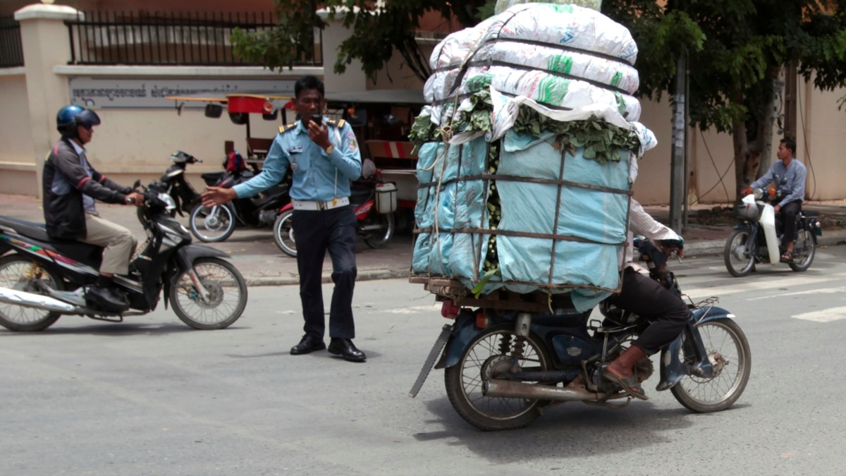 A Cambodian girl is sqeezed between a driver and a passenger of an  overloaded motorbike taxi in the capital Phnom Penh, Tuesday, April 4,  2006. Overloaded motorcycles and cars are a common