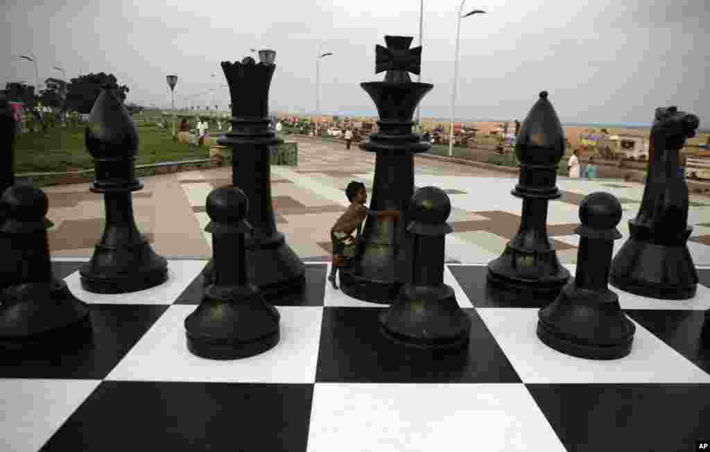 An Indian child plays around a huge chessboard model erected to mark the FIDE World Chess Championship at the Marina beach on the Bay of Bengal coast in Chennai.