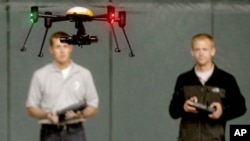 FILE - Students at the University of North Dakota in Grand Forks remotely pilot a drone during a demonstration, June 24, 2014. The Federal Aviation Administration now requires drone registration. 