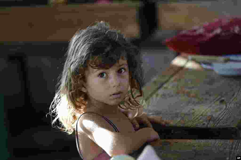Hajar Muharram, 5, sits in a classroom where the family of seven now live, at a U.N. school, in Beit Lahiya, northern Gaza Strip, Thursday, July 31, 2014.
