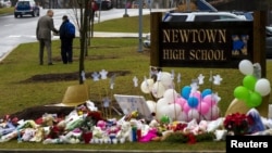 A student is consoled after he placed flowers on a memorial at the entrance to Newtown High School in Newtown, Connecticut December 18, 2012. 