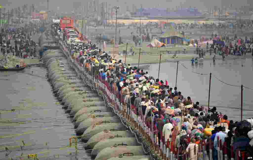 Indian Hindu devotees arrive to take a holy dip in the Sangam on the eve of &quot;Mauni Amavasya&quot; as they walk across a pontoon bridge during the annual Magh Mela festival in Allahabad.