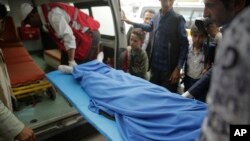FILE - Yemenis carry the body of a girl who was killed in an explosion at a warehouse in Sanaa, April 7, 2019.