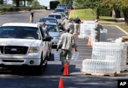 National Guard members hand out water to residents in Columbia, S.C., Oct. 6, 2015. Water distribution remained a key problem Tuesday across much of the state.