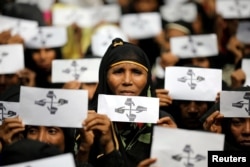 FILE - Rohingya refugee women hold placards as they take part in a protest at the Kutupalong refugee camp to mark the one-year anniversary of their exodus, in Cox's Bazar, Bangladesh, Aug. 25, 2018.