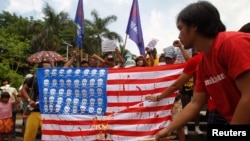 A protester burns a mock U.S. flag during a protest in Manila, April 25, 2014.