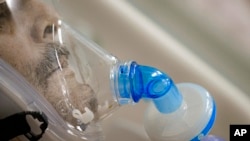 FILE - A man breathes through an oxygen mask at the COVID-19 ICU unit of the Marius Nasta National Pneumology Institute in Bucharest, Romania, Sept. 23, 2021.