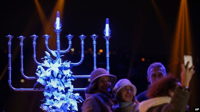 People take pictures in front of a Menorah during the Jewish festival of Hannukah, in Istanbul, Dec, 24, 2016